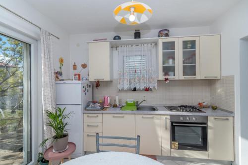 a kitchen with white cabinets and a sink and a window at Holiday Home Flower House in Kaštela