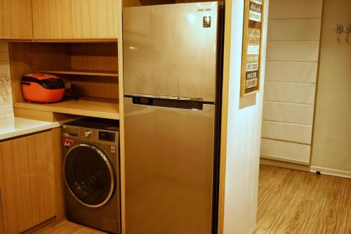 a stainless steel refrigerator in a kitchen with a washer at Graha Padma Avonia in Semarang
