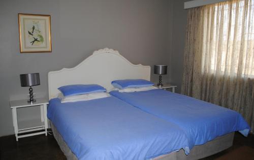 a bedroom with a large bed with blue sheets at Bateleur Nature Reserve in Modimolle