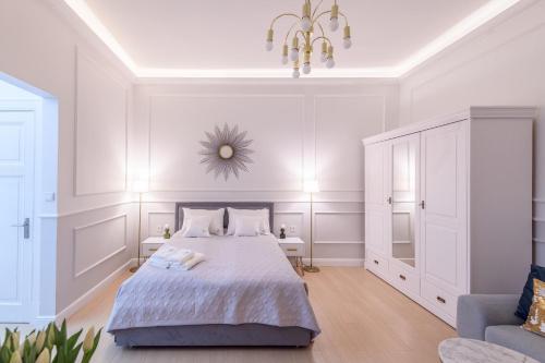 ソポトにあるJP Sopot Apartamentyの白いベッドルーム(ベッド1台、シャンデリア付)