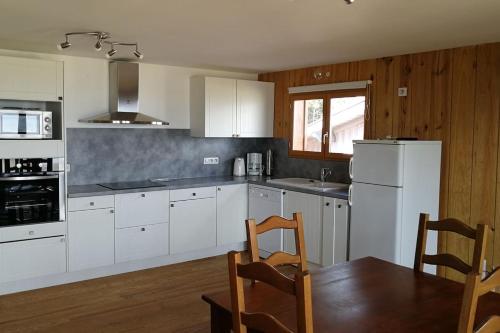 uma cozinha com electrodomésticos brancos e uma mesa e cadeiras em Cabane bord de plage em Lège-Cap-Ferret