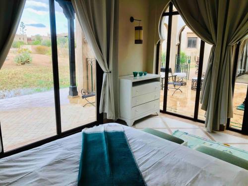 - une chambre avec un lit et des portes coulissantes en verre dans l'établissement Villa Mayrit, Villa estilo Riad en un entorno único, à Marrakech