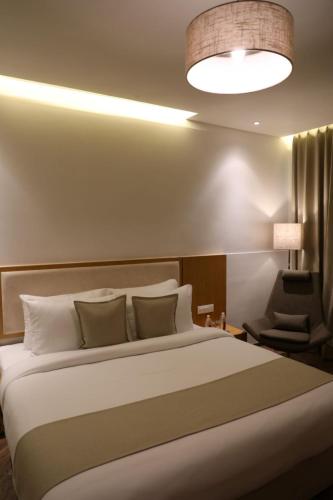 a bedroom with a large white bed and a lamp at The Fern Residency, Morbi in Morbi