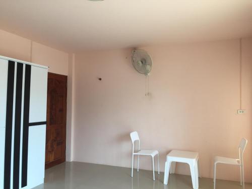 a room with two white chairs and a clock on the wall at Connexion in Ko Yao Noi