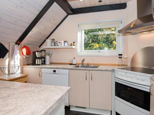 a kitchen with white cabinets and a sink and a window at 6 person holiday home in R m in Toftum