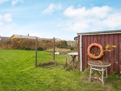 a garden with a fence and a table and an orange tire at 5 person holiday home in Thybor n in Thyborøn