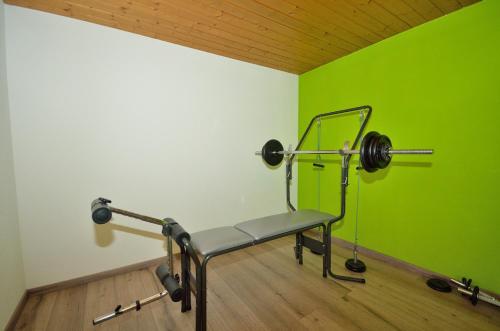 a gym with a bench and weights in a green wall at Frühstückspension Bilgeri in Sulzberg