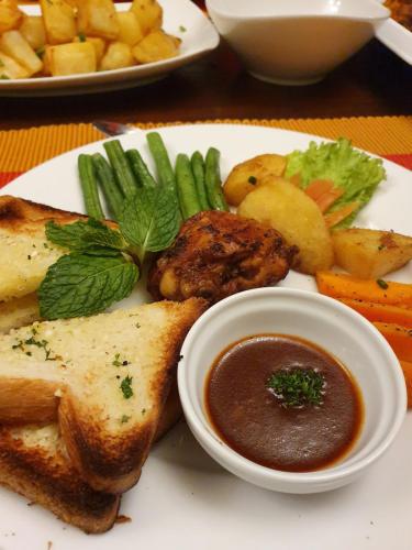 a plate of food with meat and vegetables and dipping sauce at The Walden Nuwara Eliya in Nuwara Eliya
