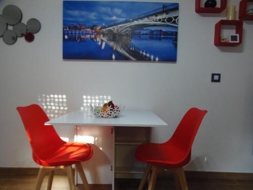 a white table with red chairs and a painting on the wall at Apartamento en Triana in Seville
