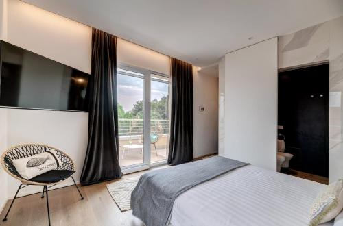 a bedroom with a bed and a chair and a window at Arveskida Suite Apartment in Cagliari