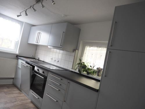 a kitchen with white cabinets and a refrigerator at KLEIN - Ferienhaus Thüringen Erfurt Apfelstädt Drei Gleichen in Apfelstädt