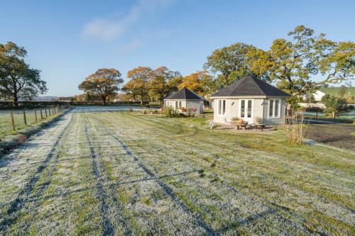 an empty field in front of a white house at Dunroamin Lodges in Drymen