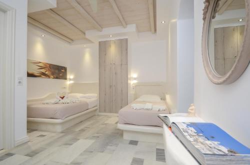 two beds in a white room with a mirror at Ostria Hotel in Agios Prokopios