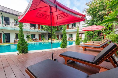 a patio with a red umbrella and chairs and a pool at Medio De Pai in Pai
