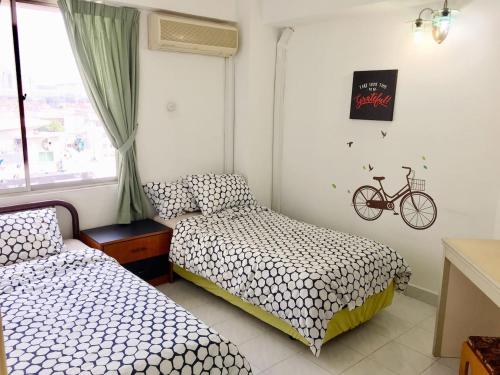 Cozy Kelana Jaya Semi-D Apt near Mall, College & Hospital في بيتالينغ جايا: غرفة نوم بسريرين ودراجة على الحائط