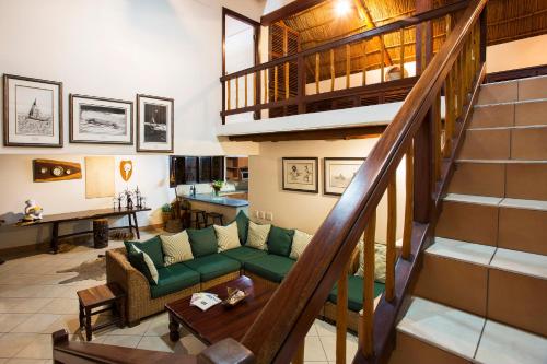 a living room with a green couch and a staircase at Vila Do Paraiso in Vilanculos