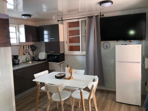 a kitchen with a white table and chairs and a refrigerator at A LA CLAIRE FONTAINE in Sainte-Suzanne