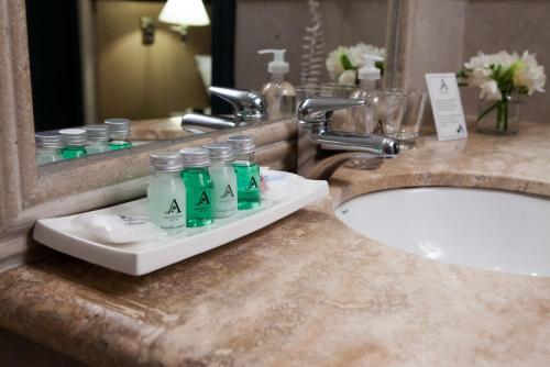 a bathroom with a sink, mirror, and soap dispenser at Argentino Hotel in Mendoza