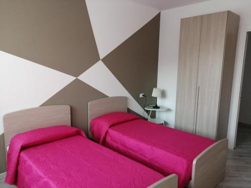 2 camas con sábanas rosas en un dormitorio en ALEXA casa vacanze, en Pero