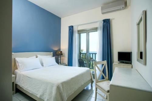 a bedroom with a bed and a window and a television at Kenta Beach Hotel in Agios Ioannis Pelio
