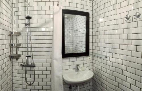Baño de azulejos blancos con lavabo y espejo en Tungulending Guesthouse en Tungulending