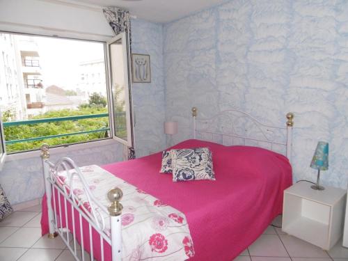 a bedroom with a pink bed and a window at Plage et jardin en centre ville in Saint-Raphaël