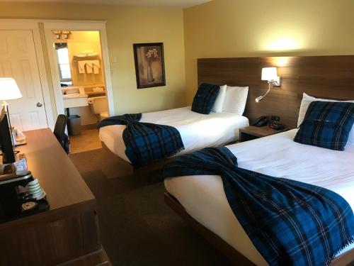 um quarto de hotel com duas camas com almofadas azuis em Inverary Resort em Baddeck