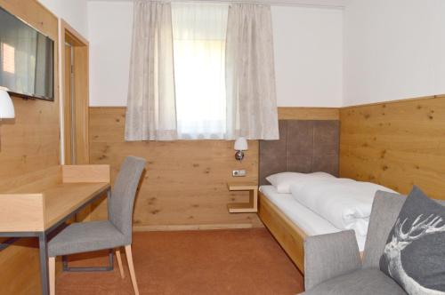 Schlafzimmer mit einem Bett, einem Schreibtisch und einem Tisch in der Unterkunft Gasthof Ramsauer in Neufahrn in Niederbayern