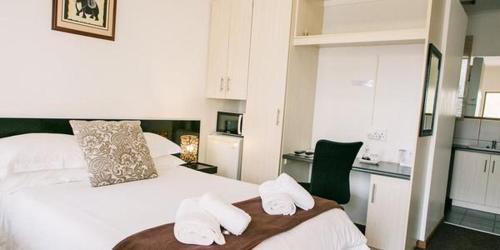a bedroom with a white bed with two towels at Pennylane Guest House in Ermelo