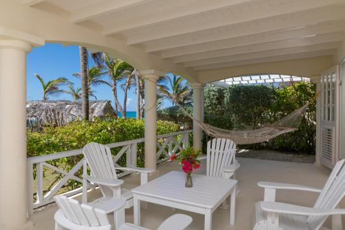 a porch with white chairs and a hammock at Inchcape Seaside Villas in Christ Church