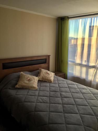 een slaapkamer met een bed met 2 kussens en een raam bij Depto Marga Marga Quilpué in Quilpué
