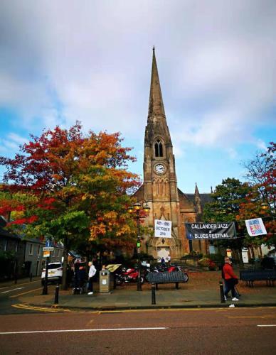 a church with a clock tower in front of it at The Caledonian Thistle Hotel in Callander
