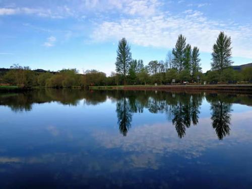 a reflection of trees in a large lake at The Caledonian Thistle Hotel in Callander