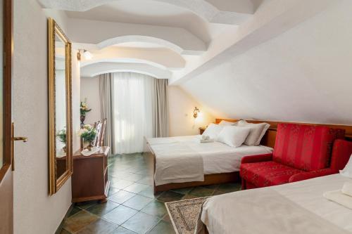 a hotel room with two beds and a red chair at Jagodic Garni Hotel in Cerklje na Gorenjskem