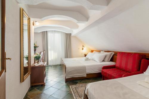 um quarto de hotel com duas camas e uma cadeira vermelha em Jagodic Garni Hotel em Cerklje na Gorenjskem