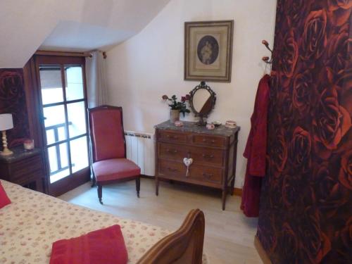 a bedroom with a dresser and a mirror and a chair at L'arum antique in Sainte-Catherine-de-Fierbois