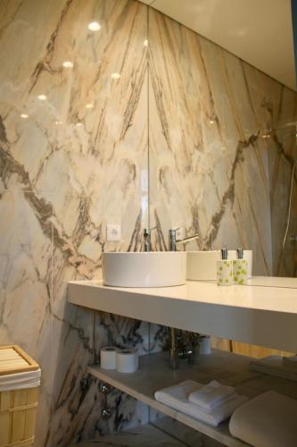 a bathroom with a sink and a marble wall at A Rendilheira Charm Suites in Vila do Conde