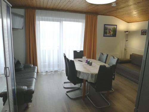 a dining room with a table and chairs and a couch at Alpenappartement Claudia in Piesendorf