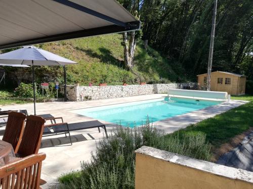 a swimming pool with two chairs and an umbrella at Villa les Bisets 497 rue de fenelon in Carlux