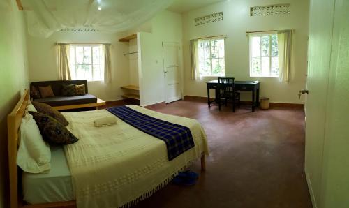 a bedroom with a bed and a couch and windows at Bwindi Guest House in Kinkizi