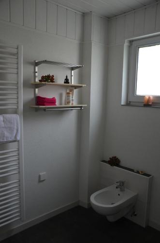 a white bathroom with a sink and a window at Ferienwohnung Klock in Weisenbach