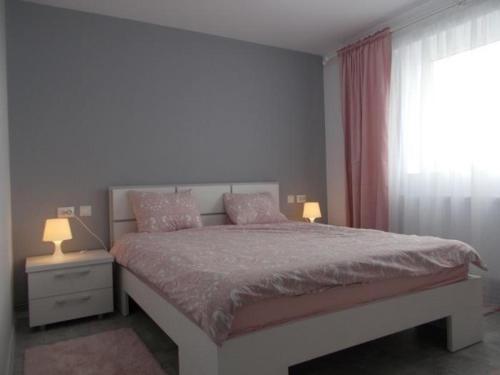 - une chambre avec un lit, deux lampes et une fenêtre dans l'établissement Apartament Tanya, à Târgovişte