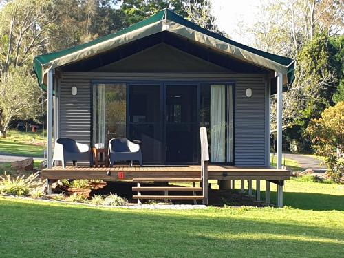 a small cabin with a table and chairs in the grass at Southern Sky Glamping in Mount Tamborine