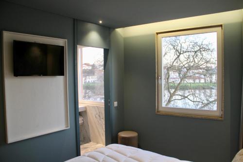 a bedroom with a window and a bed and a television at A Rendilheira Boutique Hotel in Vila do Conde