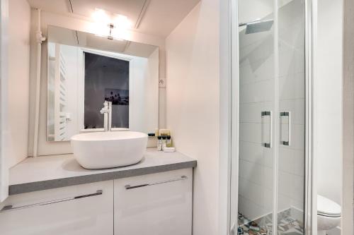 une salle de bain blanche avec un lavabo et une douche dans l'établissement Apartment 3 people close Eiffel Tower by Weekome, à Paris