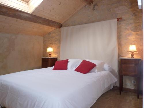 Un dormitorio con una cama blanca con dos almohadas rojas. en Le Mas des Sages, en Aubussargues