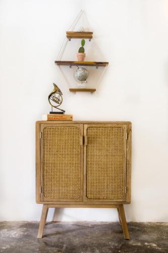a wicker cabinet against a white wall with a clock on top at La Veranda Hotel & Restaurant in Minca