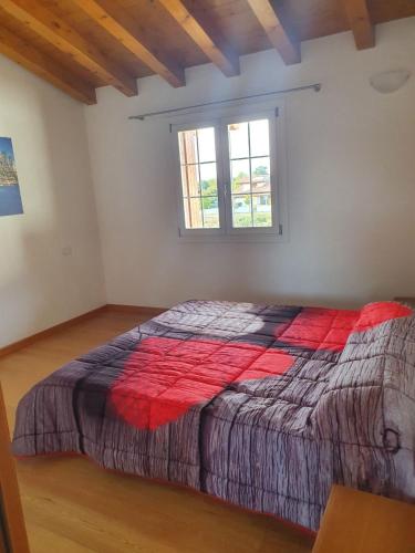 - une chambre avec un grand lit et une couverture rouge dans l'établissement Happy house villotta, à Chions