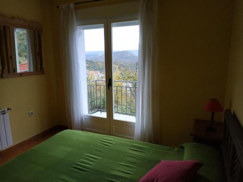 een slaapkamer met een groen bed en een groot raam bij El Taller in San Bartolomé de Tormes