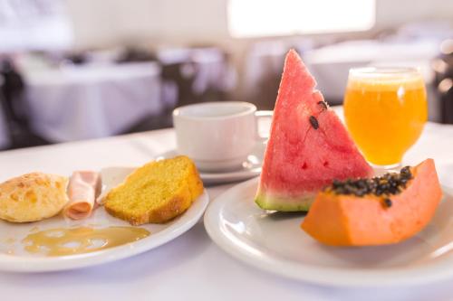 a table with two plates of food and a glass of orange juice at Hotel Londres in São Lourenço